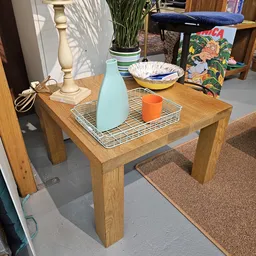 Houten salontafel met dienblad, blauwe vaas, oranje beker en decoratieve items