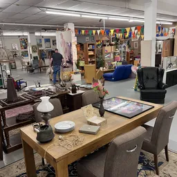 Winkelvloer met meubels, tafel, stoelen, blauwe poef en diverse decoratieve items uitgestald