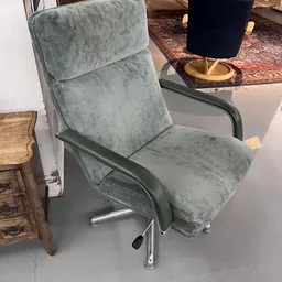 Grijze stoel met armleuningen en zwart metalen onderstel, close-up van meubelstuk in kringloopwinkel