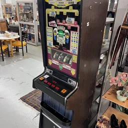 Vintage gokautomaat met kleurrijke display en speelknoppen in kringloopwinkel