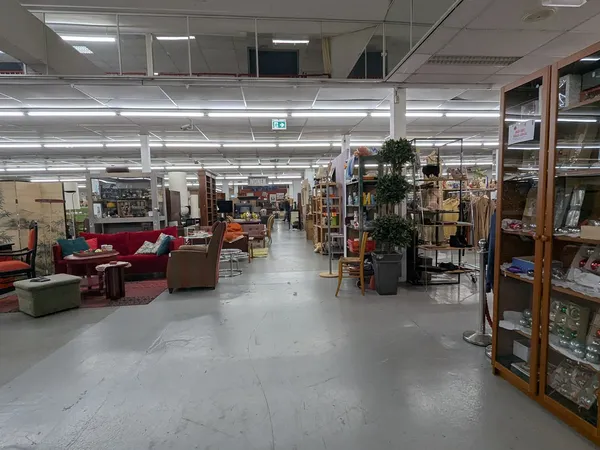Winkelvloer met stellingen, meubels en diverse tweedehandsartikelen onder fluorescerende verlichting