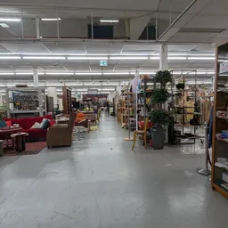 Winkelvloer met stellingen, meubels en diverse tweedehandsartikelen onder fluorescerende verlichting