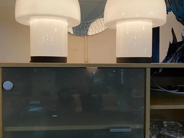 Interieur met twee witte hanglampen boven een donkere vitrine, houten stellage met items