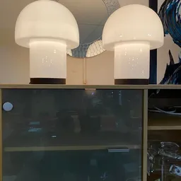 Interieur met twee witte hanglampen boven een donkere vitrine, houten stellage met items
