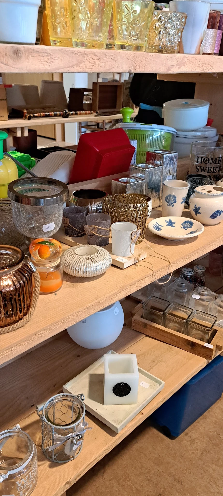 Tafel met diverse huishoudelijke artikelen: glazen potten, aardewerk servies met blauwe decoratie, woven manden, kandelaars e