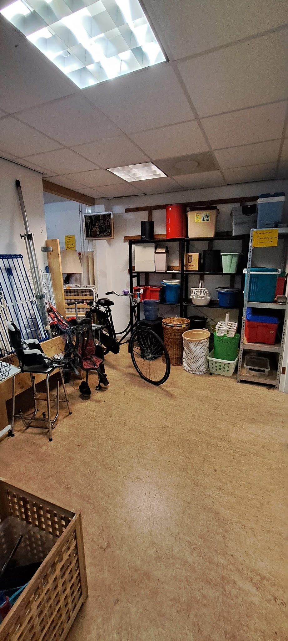 Winkelvloer met stellingen vol spullen, fiets, stoelen, manden en diverse huishoudelijke artikelen