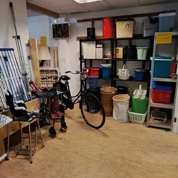 Winkelvloer met stellingen vol spullen, fiets, stoelen, manden en diverse huishoudelijke artikelen