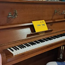 Bruine houten piano met gele notitieboeken op de klep