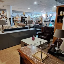 Winkelvloer met uitgestalde meubels: zwarte bank, witte salontafel, stoelen en lampen in een ruime ruimte met veel daglicht