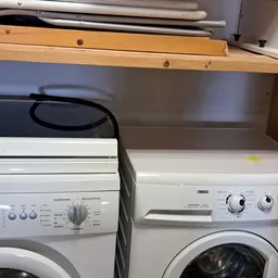 Tweedehands huishoudelijke apparaten op een plank, waaronder wasmachines en een droger