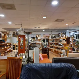 Winkelvloer van kringloopwinkel met verschillende rekken, stellingen en uitgestalde huishoudartikelen, meubels en decoratieve