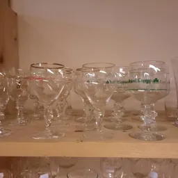 Rij glazen drinkglazen en bekers op een plank in een kringloopwinkel