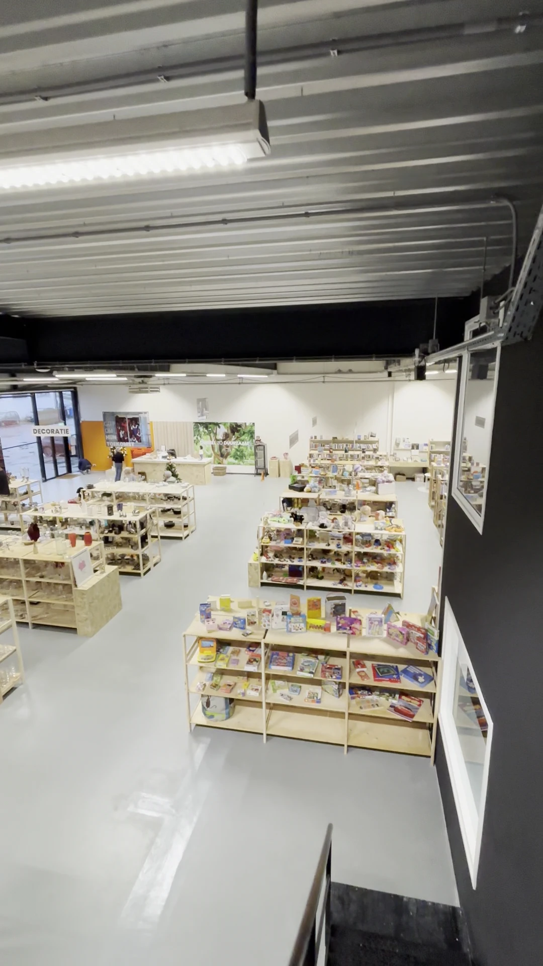 Overzicht van de winkelruimte met houten stellingen vol boeken en spullen