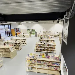 Overzicht van de winkelruimte met houten stellingen vol boeken en spullen