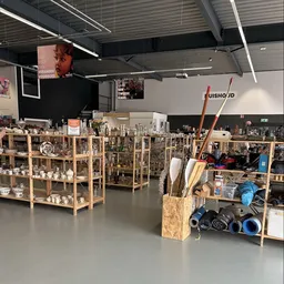 Winkelvloer met houten stellingen vol serviesgoed, kunstnijverheidsspullen en gereedschap