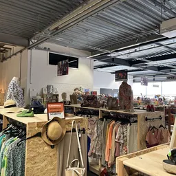 Stellingen met tweedehands kleding, tassen, hoeden en decoratieve artikelen in de winkel