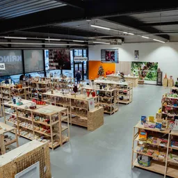 Winkelvloer met houten stellingen vol artikel's, overzicht van het assortiment van kringloopwinkel