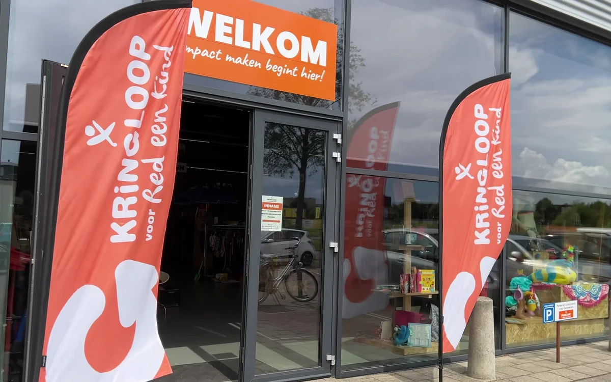 Ingang van Kringloop voor Red een Kind met rode welkomsbannersaan beide zijden van de deur