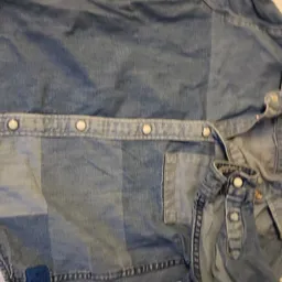 Tweedehands denimjas in verschillende blauwTinten, uitgespreid op licht oppervlak