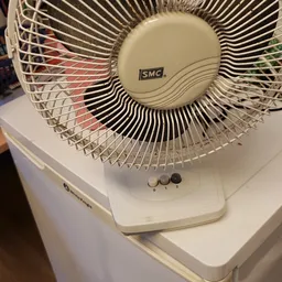 Witte tafelventilator met zwarte lamellen en controleknopen op het basispaneel