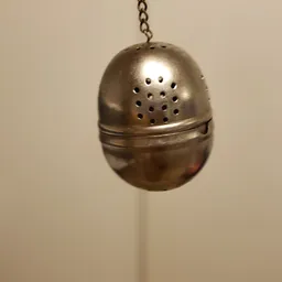 Zilveren metalen eiervormig theezeefje met gaatjes en bevestigingslus