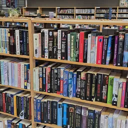 Houten boekenkast met meerdere schappen vol tweedehands boeken in verschillende kleuren en formaten.