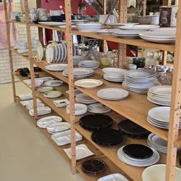 Houten stellingen volgestapeld met servies, borden en aardewerk in verschillende kleuren