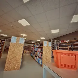 Boeken in kasten en op stellingen in een kringloopwinkel, met oranje plastic kratten op de vloer