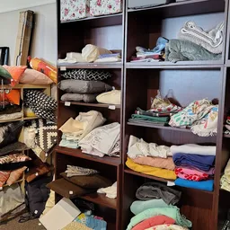 Houten kasten vol met opgestapelde kleding in verschillende kleuren en types