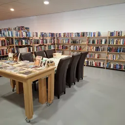 Winkelvloer met houten tafel en bruine stoelen, omringd door boekenkast met vele boeken