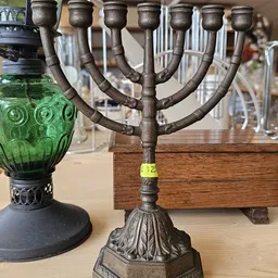 Bronzen kandelaar met meervoudige armen op houten voet, getoond in een kringloopwinkel.