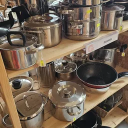 Uitgestalde pannen, potten en kookgerei op houten planken in de winkel