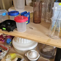 Houten plank met diverse keukengerei en plastic opbergbakken met gekleurde deksels