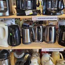 Stelling met diverse elektrische waterkokers en koffieapparaten in verschillende kleuren en stijlen