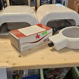 Perfectlux hairdroyer in doos op houten tafel met andere apparaten op achtergrond