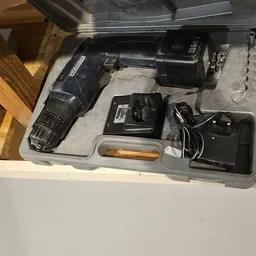Zwarte boormachine met accessoires in plastic opbergkist