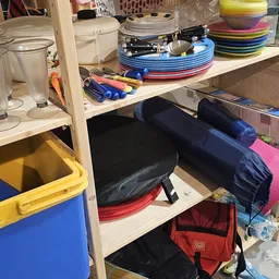 Stellingen met gestapelde borden in verschillende kleuren en diverse huishoudelijke artikelen