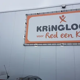Gevel van kringloopwinkel met oranje en wit logo 'Kringloop voor Red een Kind'