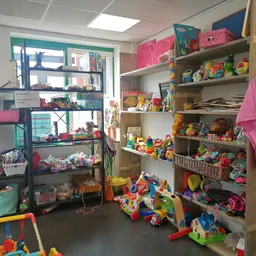 Speelgoedafdeling met houten stellingen vol gekleurde speelgoed, poppen en spellen