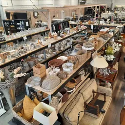 Overzicht van de winkelruimte met tafels vol huishoudspullen, servies, decoratie en secondhandartikelen