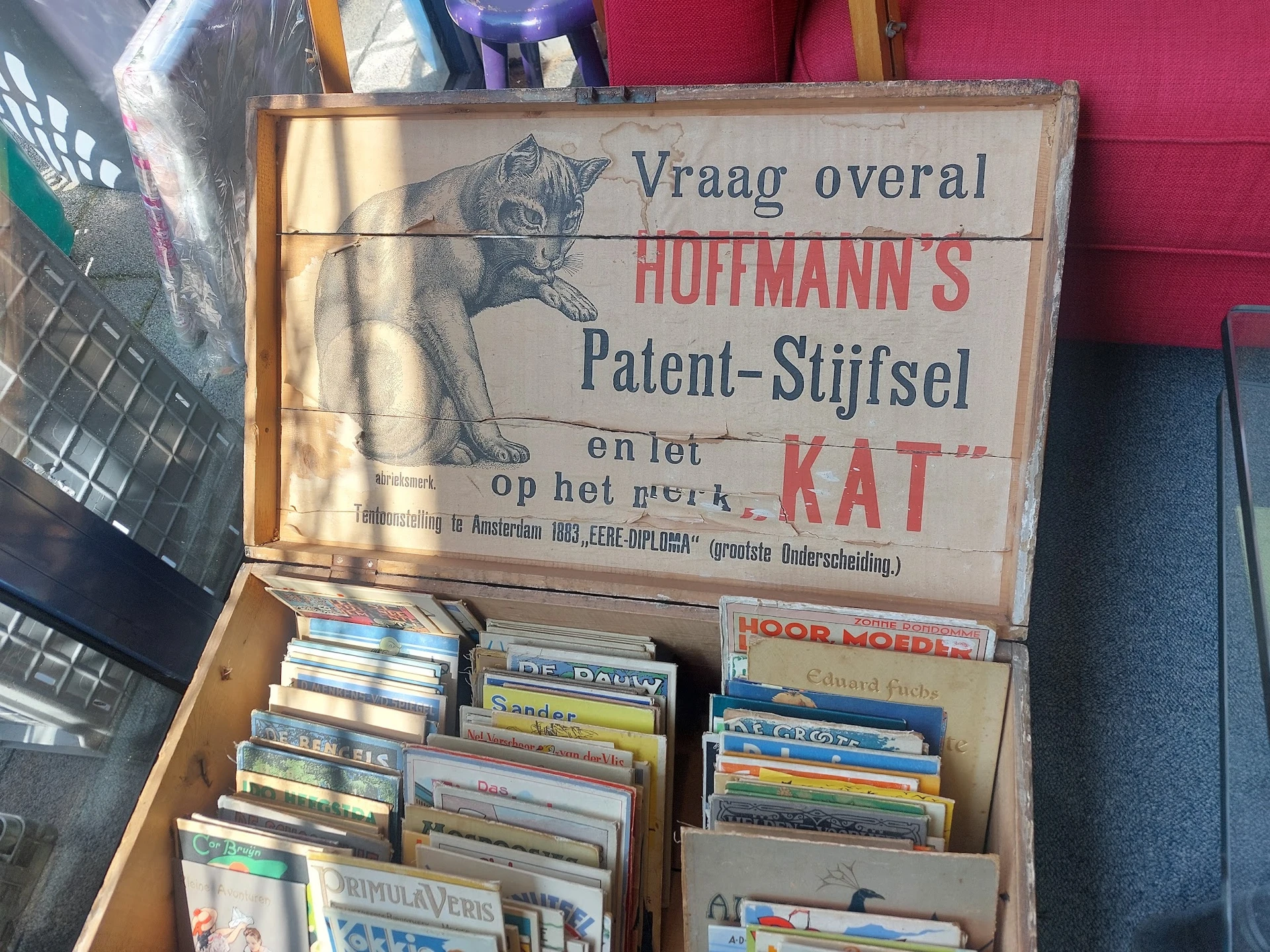 Vintage houten kist met oud Nederlands advertentiebord en stapels cd's en dvd's erin