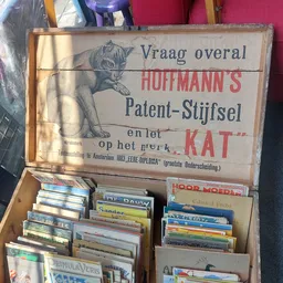 Vintage houten kist met oud Nederlands advertentiebord en stapels cd's en dvd's erin