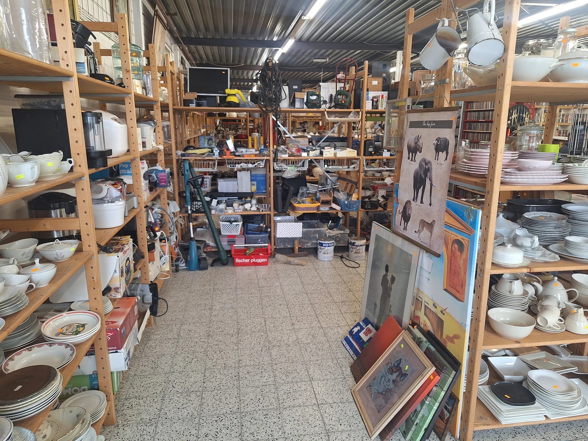 Overzicht van de winkelvloer met houten stellingen vol servies, borden, kopjes en huishoudelijke spullen