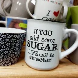 Drie koffiemugs met opdruk, waaronder één met tekst 'If you add some SUGAR LIFE will be sweeter'