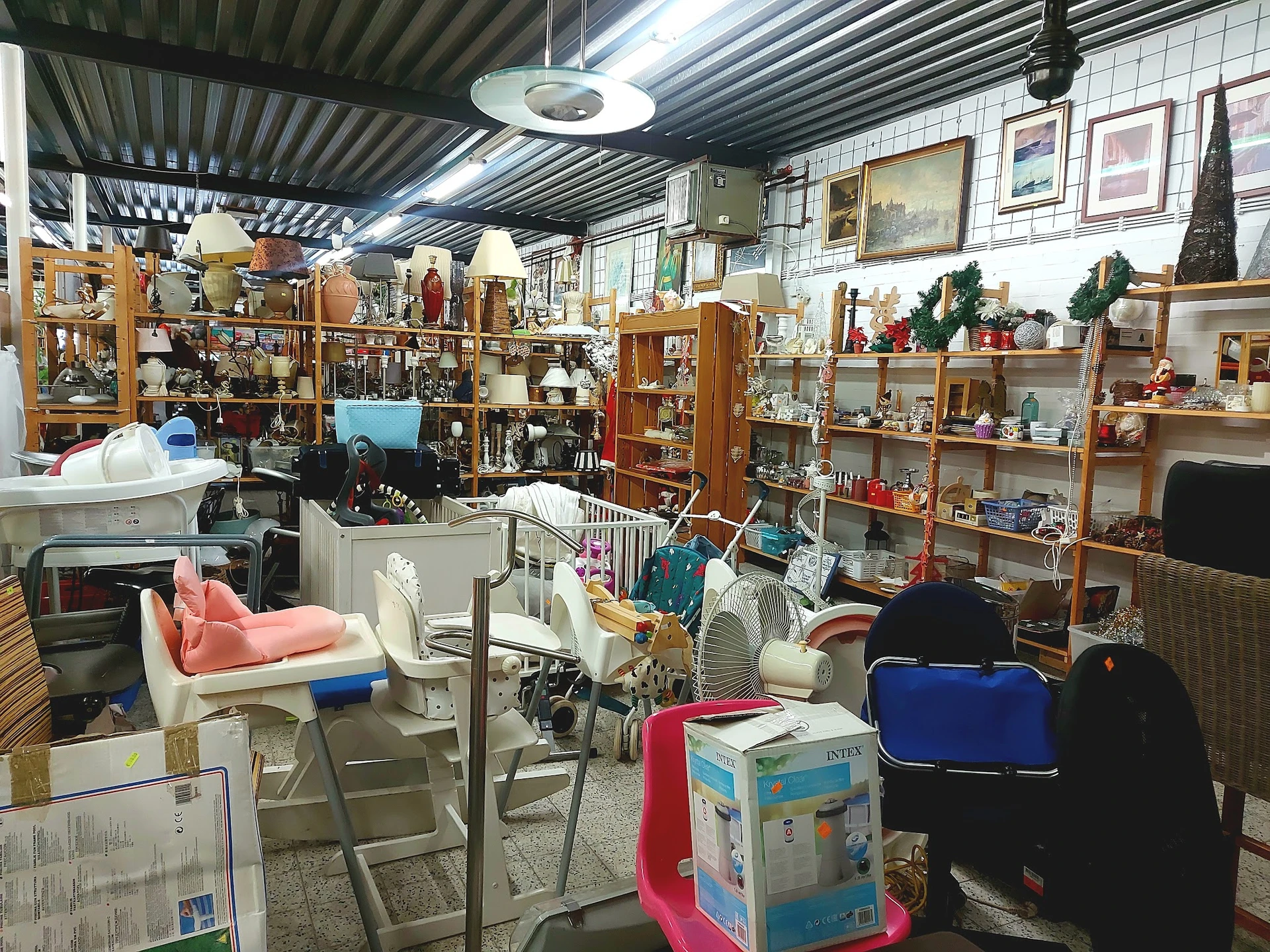 Winkelvloer met stellingen vol huishoudartikelen, meubels en decoratieve spullen in een kringloopwinkel