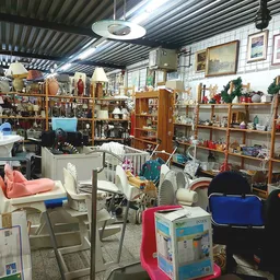Winkelvloer met stellingen vol huishoudartikelen, meubels en decoratieve spullen in een kringloopwinkel