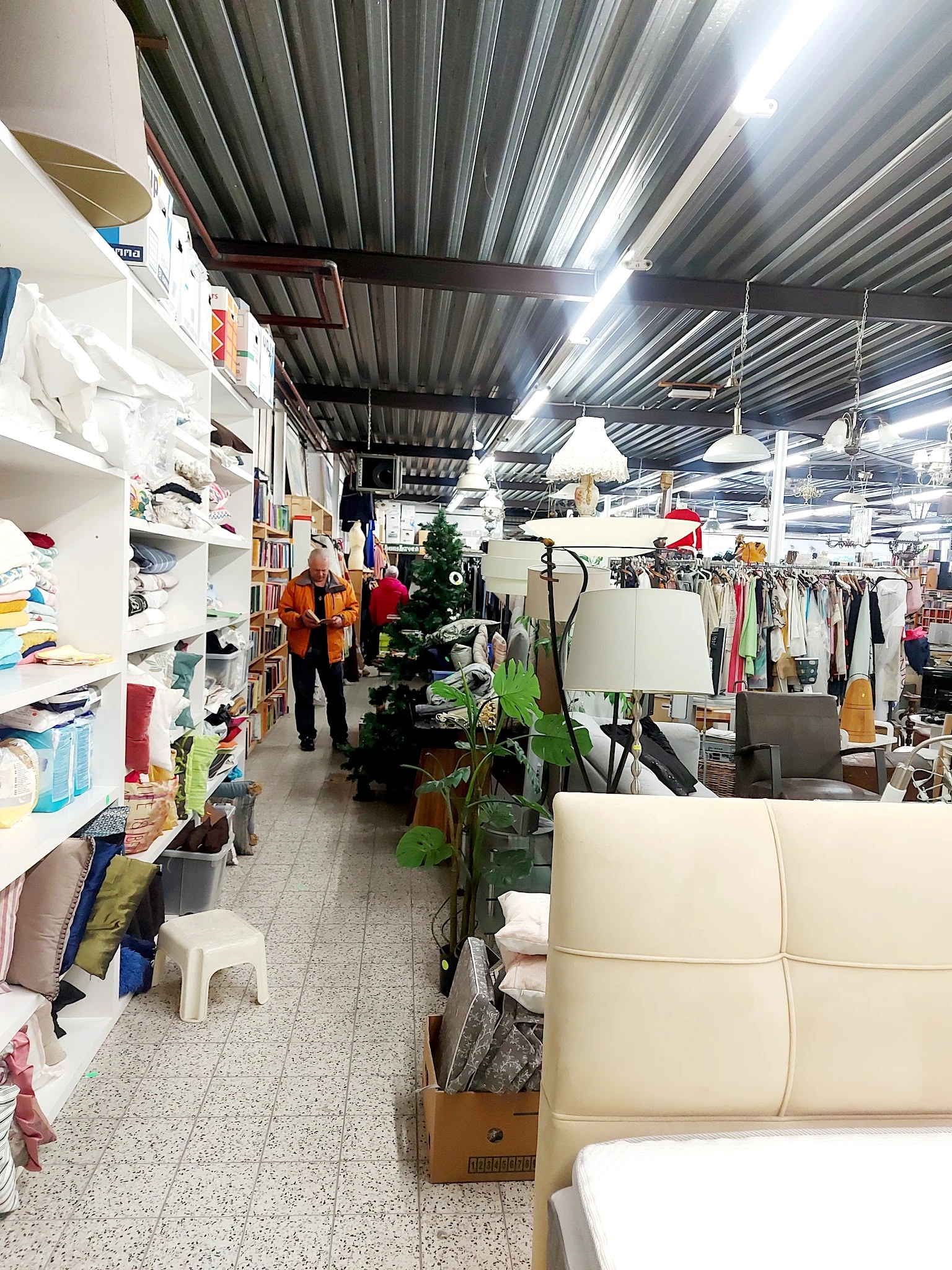 Winkelvloer van kringloopwinkel met stellingen, kleding aan rekken, meubels en diverse spullen