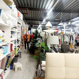 Winkelvloer van kringloopwinkel met stellingen, kleding aan rekken, meubels en diverse spullen