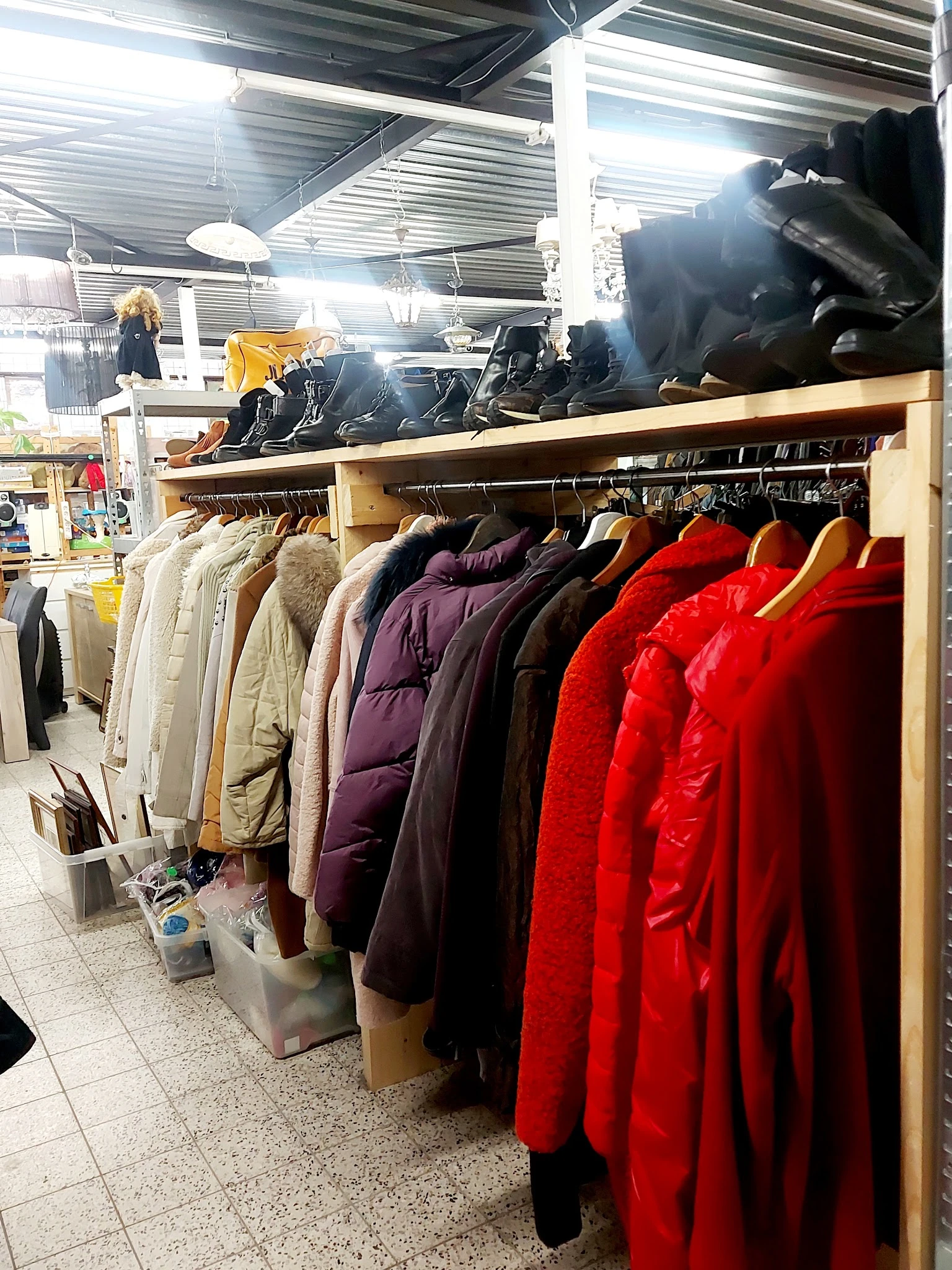 Rekken met tweedehands winterjassen in verschillende kleuren, waaronder rood, zwart, paars en beige