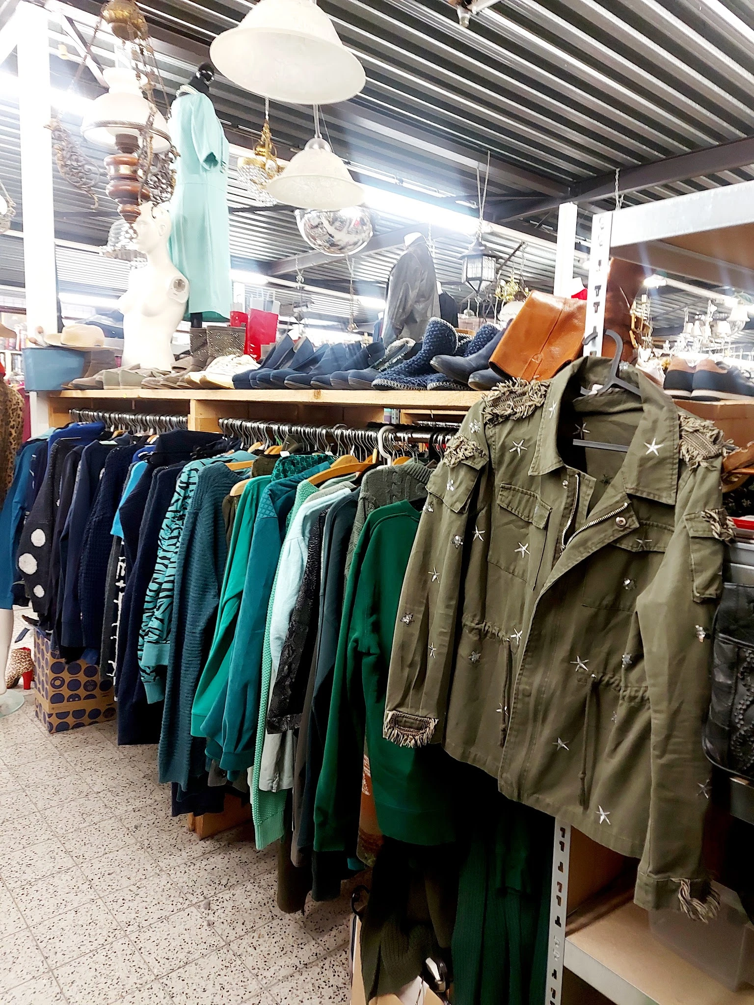 Rekken met tweedehands jassen en jasjes in verschillende kleuren, voornamelijk donkerblauw, groen en khaki